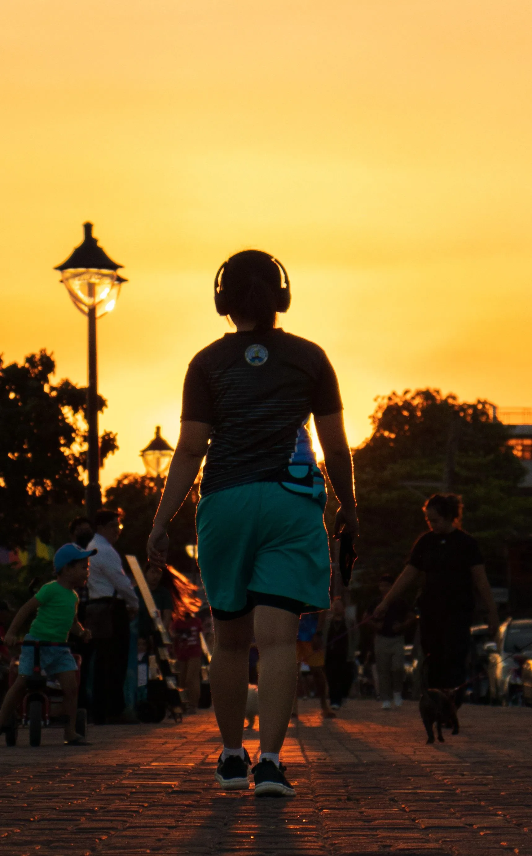 Someone walking at sunset, wearing headphones.